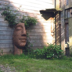 Jardin statue visage métal végétation